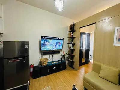 a living room with a flat screen tv and a refrigerator at 1 Bedroom with balcony Near Airport Bgc Taguig City in Manila