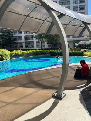 a person sitting under an umbrella next to a swimming pool at 1 Bedroom with balcony Near Airport Bgc Taguig City in Manila