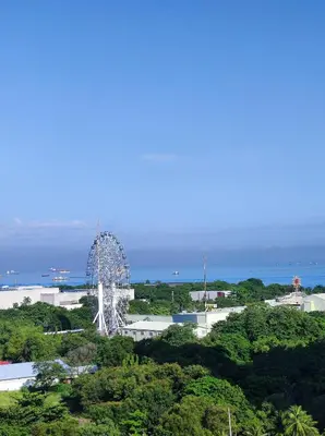 a large white ferris wheel in the middle of trees at Schönes Apartment mit Pool-Nutzung in Manila