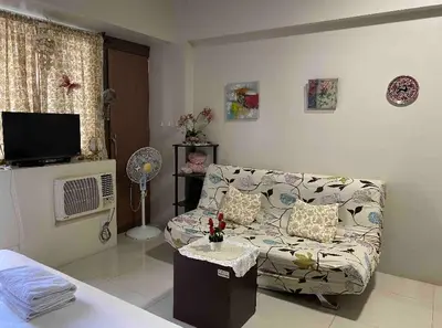 a living room with a couch and a tv at S&S CondoTel STUDIO TYPE One Palm Tree Villas in Manila