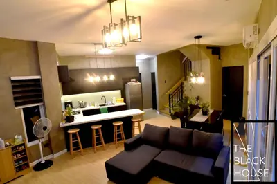 a living room with a couch and a kitchen with a counter at The Black House in Dulong Bayan