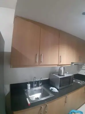 a kitchen counter with a sink and wooden cabinets at SHELL RESIDENCE C1 shortwalk MALL OF ASIA NEAR AIRPORT in Manila