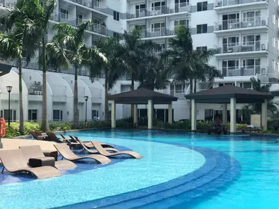 a swimming pool with lounge chairs and a building at MOA CONDOTEL MANILA in Manila