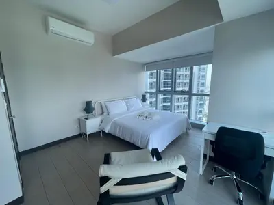 a bedroom with a bed and a desk and a chair at Bright 2-bedroom condo with pool in BGC Uptown in Manila