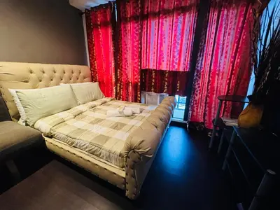 a bed in a room with red curtains at Gramercy Residences studio with Balcony Netflix in Manila