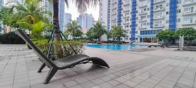 a hammock chair sitting next to a swimming pool at 1BR Suite @ SM Jazz Residences - WIFI & Netflix in Manila