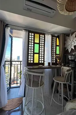 a kitchen with a bar with chairs and windows at Balay Sa Air, Beyond Ordinary at Air Residences Makati in Manila
