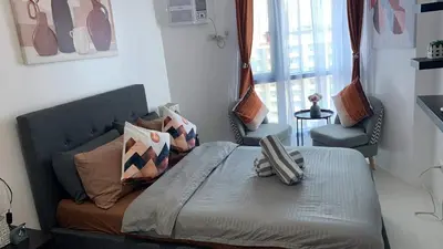 a bedroom with a bed with two chairs and a window at Grand Riviera Suites Comfy Condo near US Embassy Manila Bay Roxas Blvd Ermita Manila in Manila
