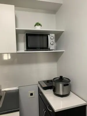 a small kitchen with a stove and a microwave at Cozy 1 Bedroom near Alabang Town Center and Molito with Wifi and Netflix in Manila