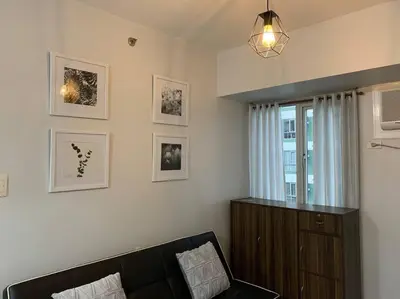 a living room with a couch and a window at Cozy 1 Bedroom near Alabang Town Center and Molito with Wifi and Netflix in Manila