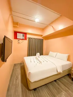 a bedroom with a large bed with a tv on the wall at Kaizen Suites in Manila