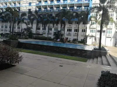 a large building with a swimming pool in front of it at Bliss Staycation at Sea Residences by John in Manila