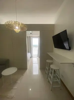 a living room with two stools and a table and a television at 1BR unit in South Residence Las Pinas with Wifi & Netflix in Manila