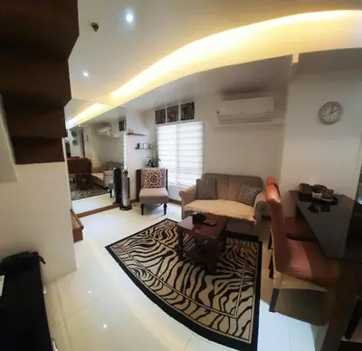 a living room with a couch and a table at 2 BR loft-type condo Fort Victoria in Manila