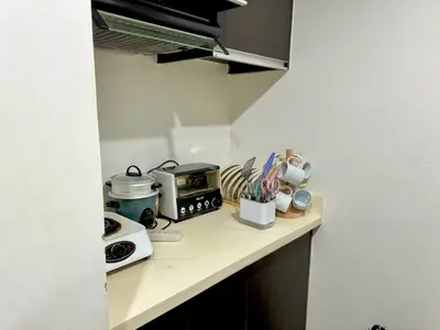 a kitchen counter with a counter top with a microwave at 2BR w Balcony in Araneta, Cubao w Pool and Gym - Porto Vita in Manila