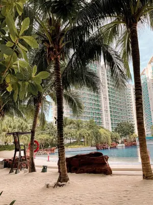 two palm trees on a beach with a large building at Downtown Nook - Azure Urban Resort Residences in Manila