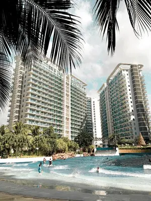 a group of people in the water at a beach with buildings at Downtown Nook - Azure Urban Resort Residences in Manila