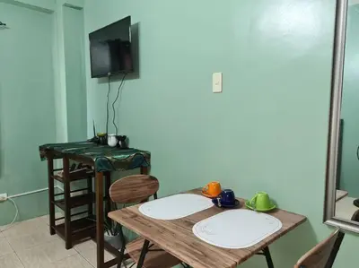 a dining room table with two chairs and a television at Affordable staycation in Valleygolf in Cainta