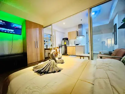 a bedroom with a large bed with a television on it at Azure Pool View with Balcony, WiFi and Netflix in Manila