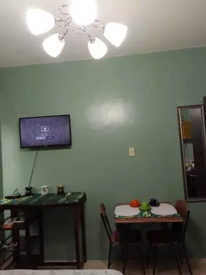 a living room with two tables and a tv on the wall at Pet Friendly Transient in Valley Golf near Emperor Events Place in Cainta
