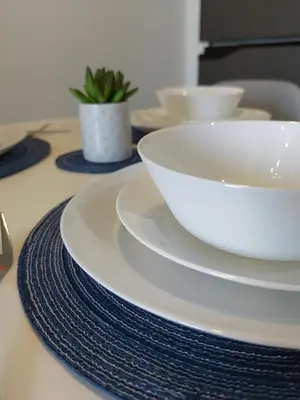 a table with white bowls and plates on it at Happirest at Azure Urban Resort Residences, Paranaque City in Manila