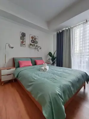 a bedroom with a large green bed with pink pillows at Happirest at Azure Urban Resort Residences, Paranaque City in Manila