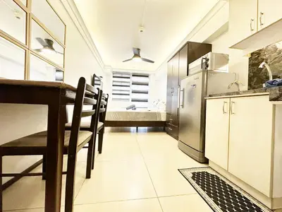 a kitchen with a table and a stainless steel refrigerator at SweetSuites at Pine Crest #T1-526 in Manila