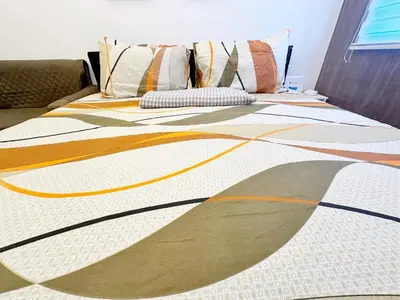 a bed with an orange and white blanket on it at King Bed Suite at Pine Crest #T3-439 near Mall in Manila