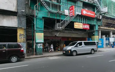 two cars parked on a street in front of a building at RedDoorz @ Riches Holiday Hotel Avenida in Manila