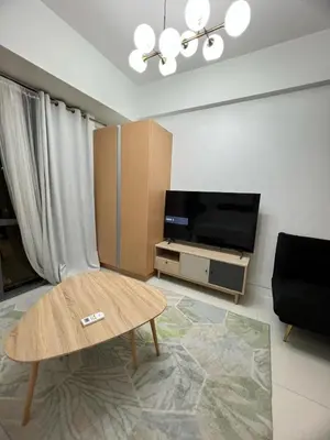 a living room with a coffee table and a flat screen tv at 1BR Studio at viceroy McKinley taguig in Manila