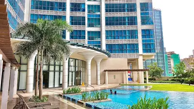 a building with a swimming pool in front of a building at Lovely 1 Bedroom City View in Uptown BGC in Manila