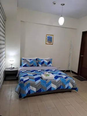 a bedroom with a bed with blue and white pillows at RQUI CONDOTEL NEAR AIRPORT & Resorts World Manila in Manila