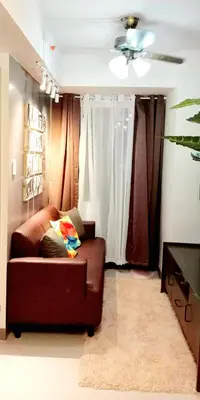 a living room with a brown couch and a ceiling fan at MOA S Residences 1BR Condo Stunning Boutique T3 in Manila