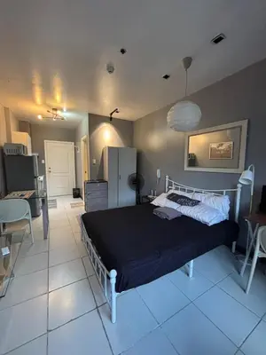 a bedroom with a bed and a room with a kitchen at Makati - Sleeps 2 - Pool - Cinema - Gym - Garden in Manila
