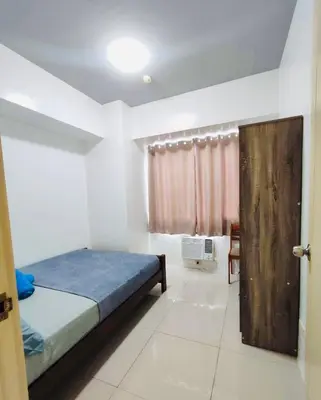 a bedroom with a bed and a wooden door at Lyndon at Sea Residences, SMDC MOA Complex, Pasay City, Philippines in Manila