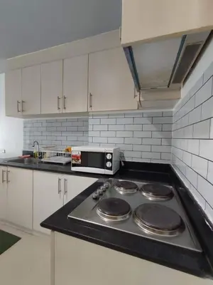 a kitchen with a stove top with a microwave at Lyndon at Sea Residences, SMDC MOA Complex, Pasay City, Philippines in Manila