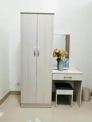 a white cabinet next to a desk with a vase of flowers at Staycation by Janeil at Shore 2 Residences SMDC, MOA Complex, Pasay City, Philippines in Manila