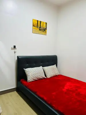 a black bed with a red blanket and two pillows at OneTiago Staycation - Spring Residences Paranaque in Manila
