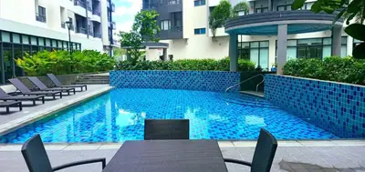 a swimming pool in a building with chairs and a table at OneTiago Staycation - Spring Residences Paranaque in Manila