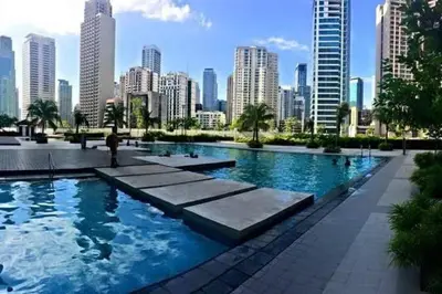 a large swimming pool with a city in the background at Jazz Residences by Destina Stays, Makati, Metro Manila in Manila