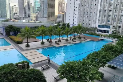 a large pool with palm trees in a city at Jazz Residences by Destina Stays, Makati, Metro Manila in Manila