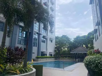 a hotel with a swimming pool in front of a building at Studio at viceroy t4 Florence way in Manila