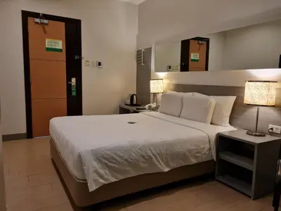 a bedroom with a large white bed and a lamp at Go Hotels Otis - Manila in Manila