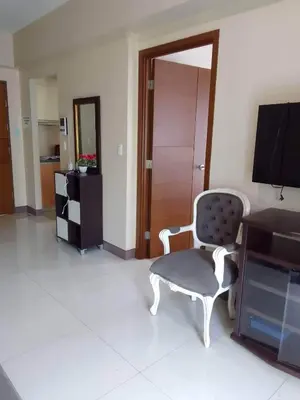 a living room with a chair and a television at MRMCONDOTEL in Manila