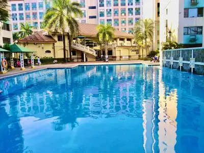 a large blue swimming pool with buildings in the background at IV’s Condo w/ Netflix, Wifi & Karaoke in Cainta