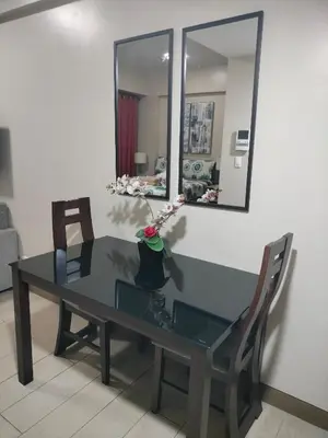 a glass table with two chairs and a mirror at RQUI CONDOTEL NEWPORT PASAY in Manila