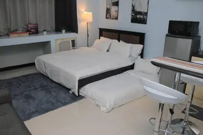 a bedroom with a large bed and a table and a desk at A2J Executive Studio Suite Near Venice Mall BGC in Manila