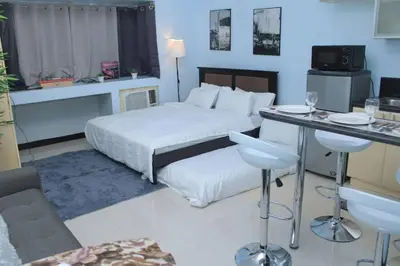 a hotel room with a bed and a table and chairs at A2J Executive Studio Suite Near Venice Mall BGC in Manila