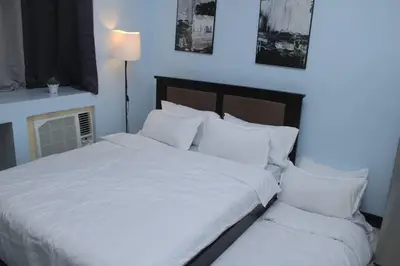 a bed with white sheets and pillows in a room at A2J Executive Studio Suite Near Venice Mall BGC in Manila