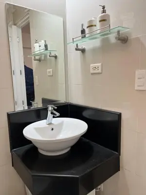 a bathroom with a white sink and a mirror at Telly's Studio Across NAIA3 in Manila